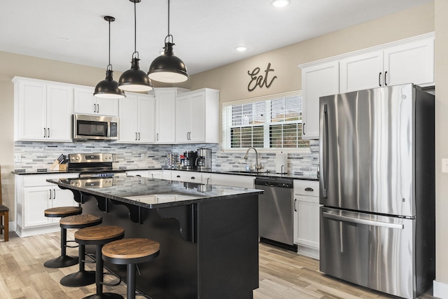 kitchen with decorative backsplash, appliances with stainless steel finishes, a sink, and white cabinets