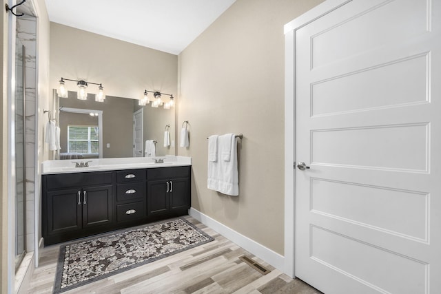 bathroom with wood-type flooring, a shower with door, and vanity