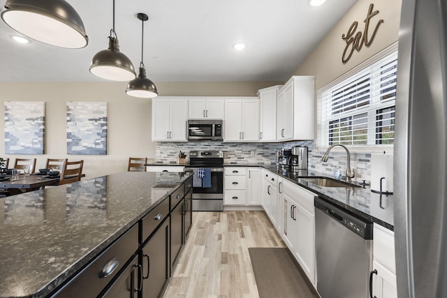 kitchen featuring white cabinets, dark stone countertops, sink, pendant lighting, and appliances with stainless steel finishes