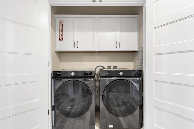 washroom with washer and dryer and cabinets