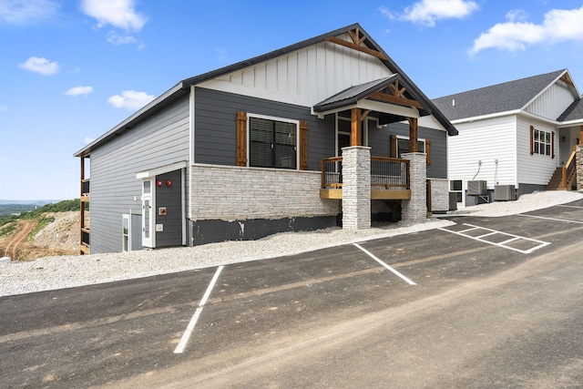 view of front of home featuring board and batten siding, uncovered parking, and stone siding