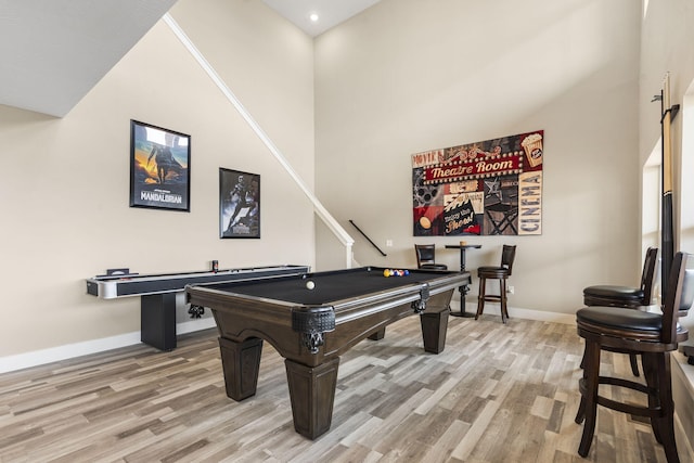 rec room featuring hardwood / wood-style flooring, pool table, and a towering ceiling