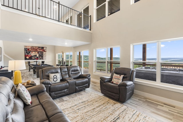 living room featuring a towering ceiling, light hardwood / wood-style floors, and billiards