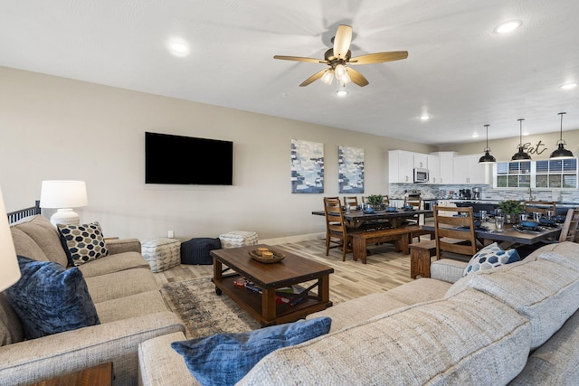 living area with light wood-type flooring, baseboards, recessed lighting, and ceiling fan