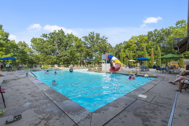 community pool with fence, a patio area, and a water slide