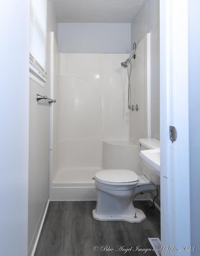 full bath featuring toilet, wood finished floors, a shower, and baseboards