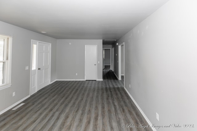 empty room featuring baseboards, wood finished floors, and visible vents