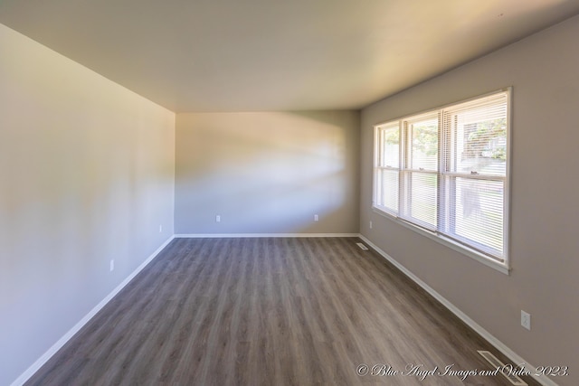 spare room featuring baseboards and dark wood-style floors