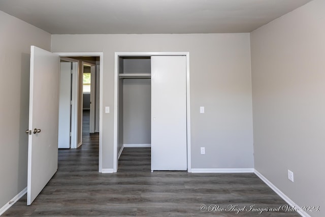 unfurnished bedroom with baseboards, dark wood-type flooring, and a closet