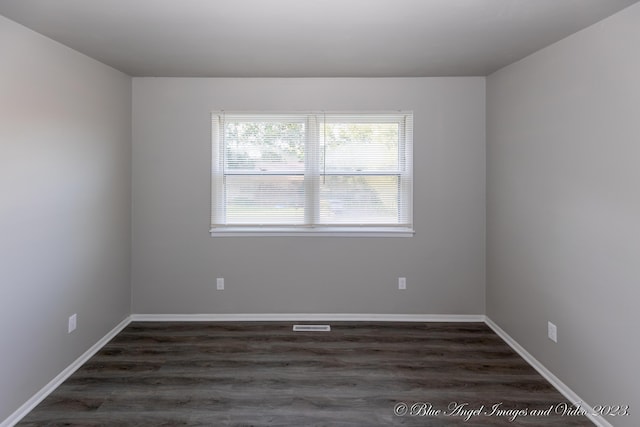 spare room with baseboards, dark wood-type flooring, and visible vents