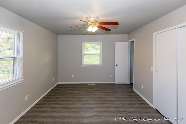 unfurnished bedroom with baseboards, multiple windows, and dark wood-style floors