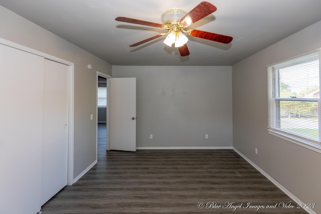 unfurnished bedroom featuring baseboards, a closet, a ceiling fan, and dark wood-style floors