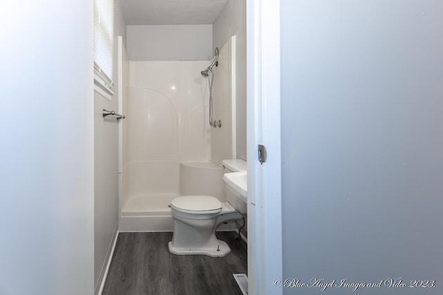 full bathroom with baseboards, wood finished floors, toilet, and a shower