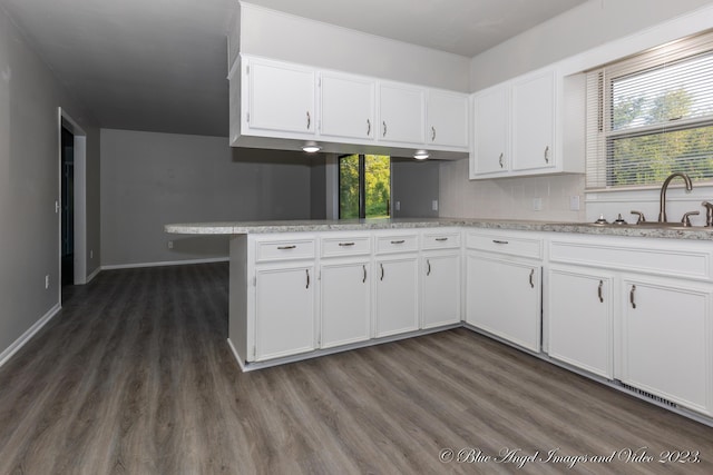 kitchen with light countertops, white cabinets, dark wood-style flooring, and a sink