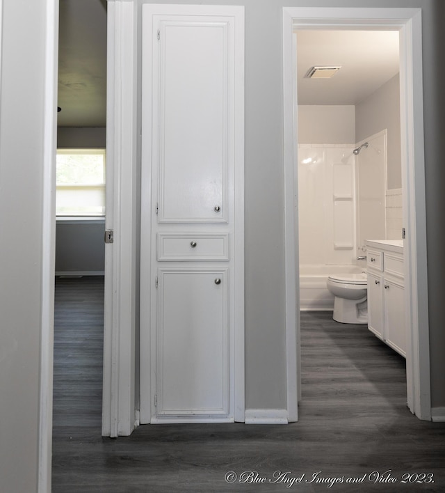 corridor featuring baseboards, dark wood-style flooring, and visible vents