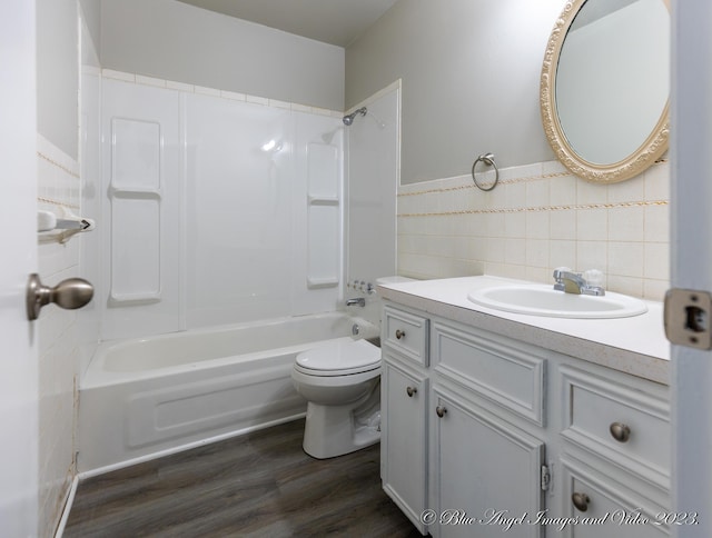bathroom featuring shower / washtub combination, wood finished floors, toilet, vanity, and tile walls