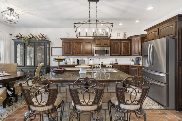 kitchen with dark brown cabinetry, stainless steel appliances, sink, and an island with sink