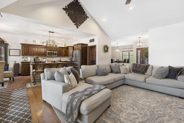 living room featuring dark wood-type flooring, a chandelier, and high vaulted ceiling