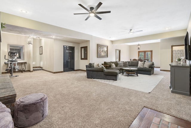 carpeted living room with ceiling fan with notable chandelier