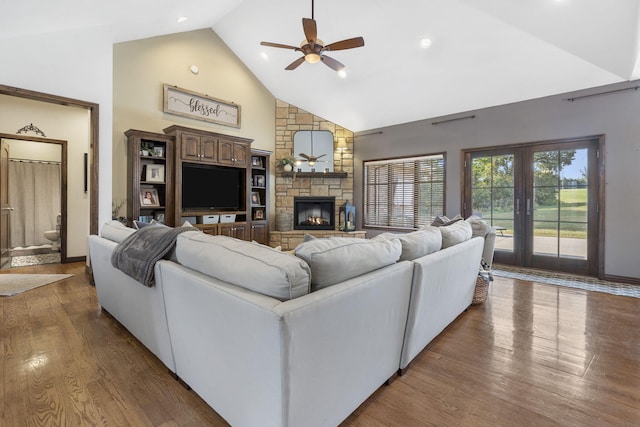 living room with plenty of natural light, dark hardwood / wood-style floors, a stone fireplace, and high vaulted ceiling