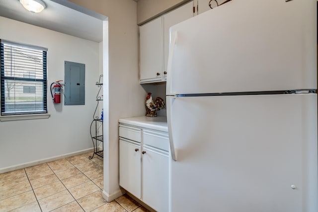 kitchen featuring white refrigerator, electric panel, light tile patterned floors, and white cabinetry