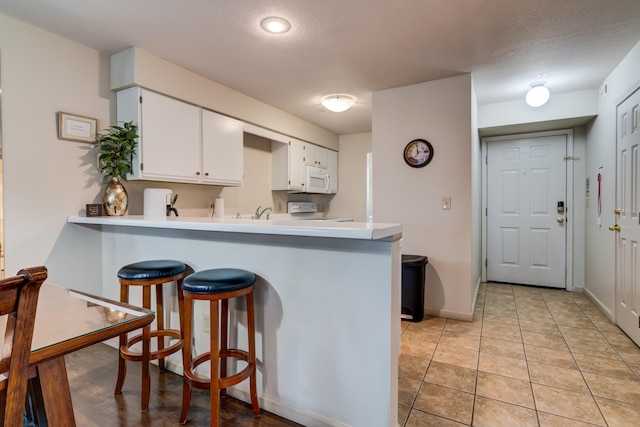 kitchen with stove, kitchen peninsula, a textured ceiling, and white cabinets