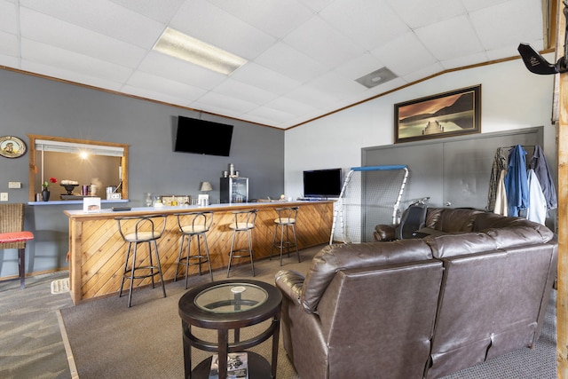 carpeted living room with vaulted ceiling, bar, and ornamental molding