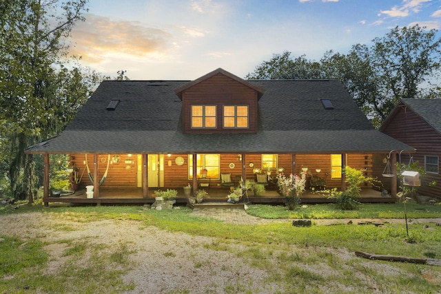 back house at dusk featuring a porch and a yard