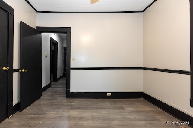 spare room featuring baseboards, crown molding, and wood finished floors