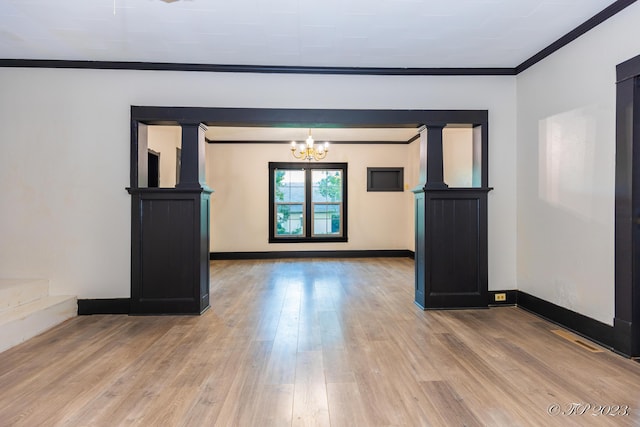 spare room featuring baseboards, wood finished floors, a chandelier, and ornamental molding
