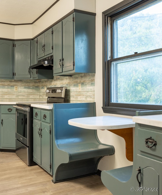 kitchen featuring light wood-style flooring, tasteful backsplash, stainless steel electric range oven, light countertops, and under cabinet range hood