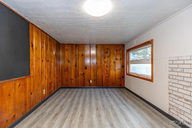 unfurnished room with wooden walls, wood finished floors, and a textured ceiling