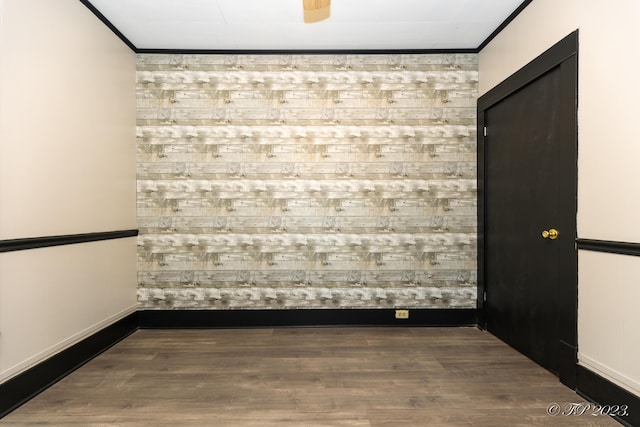 unfurnished room with wood finished floors, baseboards, and crown molding