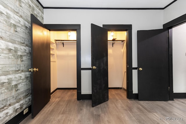 unfurnished bedroom featuring a spacious closet, crown molding, and wood finished floors