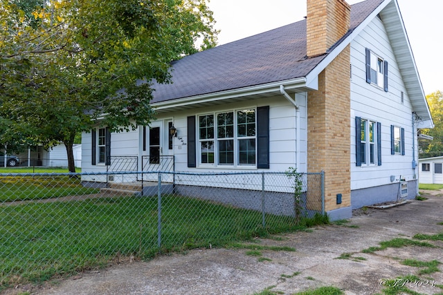 view of front of house featuring a shingled roof, a chimney, and a fenced front yard