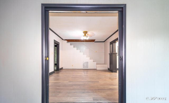 hallway with stairway, crown molding, wood finished floors, baseboards, and visible vents
