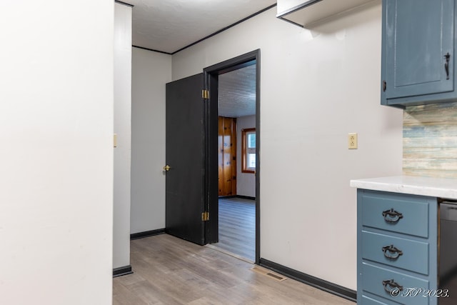 hall with baseboards, visible vents, and light wood finished floors