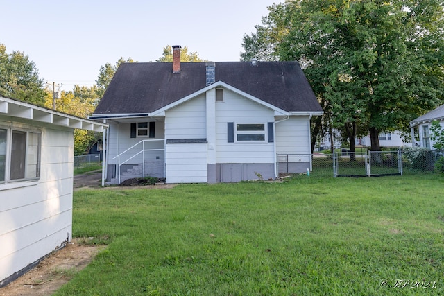 back of house featuring a yard, roof with shingles, a chimney, and fence