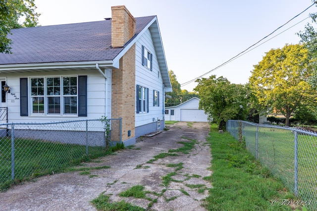 view of side of home featuring a chimney, fence, a garage, an outdoor structure, and a yard