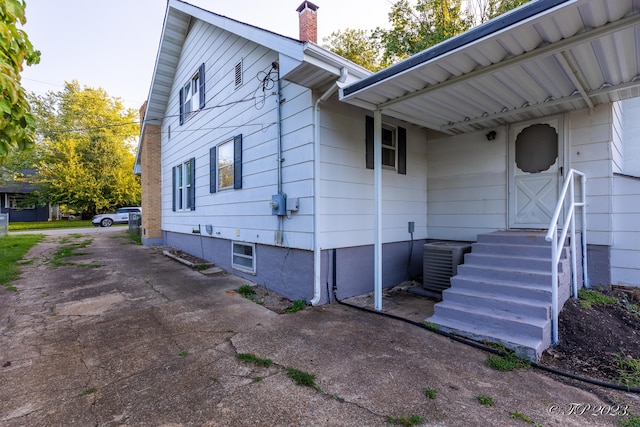 view of side of property with a chimney and central air condition unit