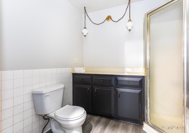 full bathroom with toilet, tile walls, wood finished floors, a shower stall, and vanity