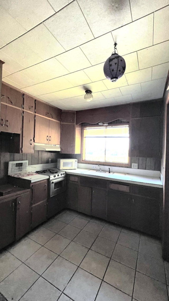 kitchen with range, dark brown cabinets, sink, and light tile patterned floors