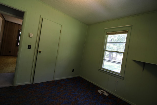 carpeted spare room with a textured ceiling and crown molding