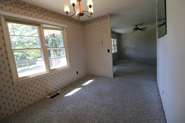 spare room featuring ceiling fan with notable chandelier and carpet floors