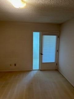 spare room featuring light hardwood / wood-style floors and a textured ceiling