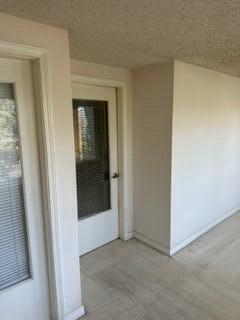 hallway featuring light colored carpet and a textured ceiling