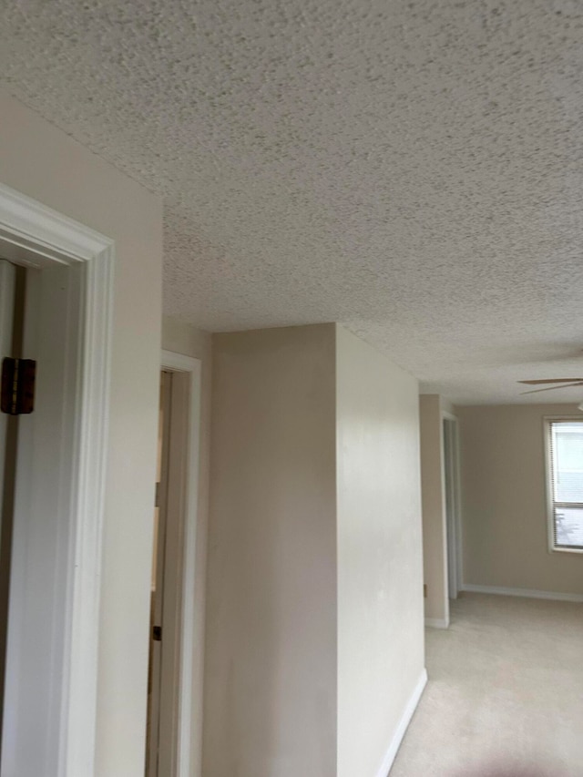 corridor featuring light carpet and a textured ceiling