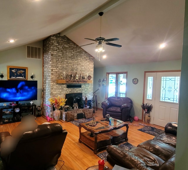 living room with wood-type flooring, a fireplace, lofted ceiling with beams, and ceiling fan