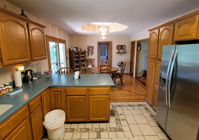1201 Railey Creek Rd, Reeds Spring, MO 65737 - kitchen with a peninsula, a chandelier, brown cabinets, stainless steel fridge with ice dispenser, and light tile patterned floors