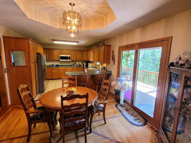 dining space featuring light hardwood / wood-style flooring, a chandelier, and a tray ceiling